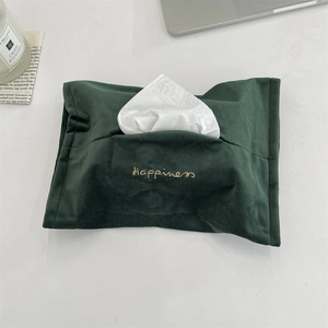 Detail of dark green velvet tissue holder with Happiness gold embroidery on a desk