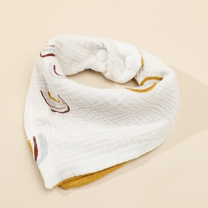 Four-layer cotton gauze baby bib with rainbow print and adjustable snaps on beige background