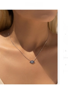 Macro shot of silver sterling evil eye necklace with blue crystals on model neckline