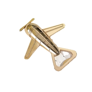 Golden vintage airplane bottle opener made of polished metal on white background