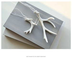 Detailed view of white matte reindeer antler ornaments set on books for Christmas decor