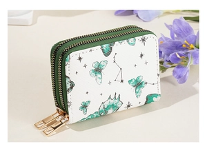 Détail du portefeuille blanc à double zip avec motifs de papillon vert et étoiles
