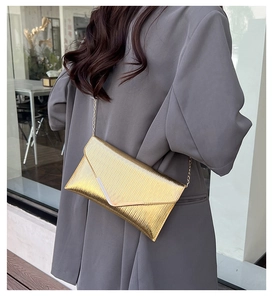 Détail de la pochette enveloppe dorée avec plis texturés et bandoulière chaîne dorée