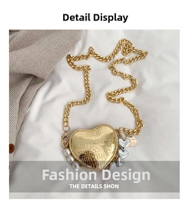 Détail du sac coeur doré motif serpent avec perles blanches et grosse chaîne en métal
