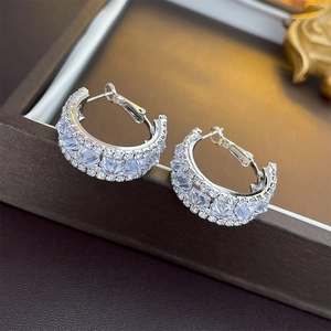 Detail view of silver C-hoop earrings featuring square cut cubic zirconia on a jewelry box