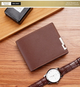 Close-up of brown litchi grain leather wallet with orange stitching on wood background