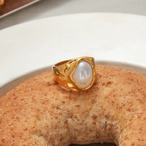 Close-up of a 18K gold plated hammered ring with oval pearl on a bagel background