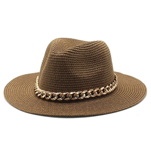 Detailed close-up of dark brown straw fedora with decorative gold metal chain trim