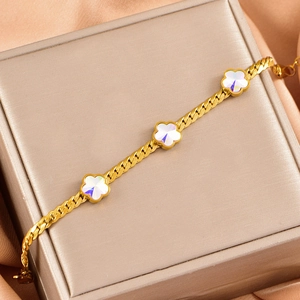 Macro shot of gold charm bracelet with iridescent floral pendants on a gift box
