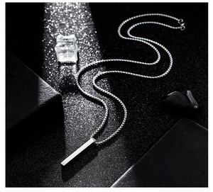 Detailed view of silver titanium steel pillar pendant necklace on a sleek black background