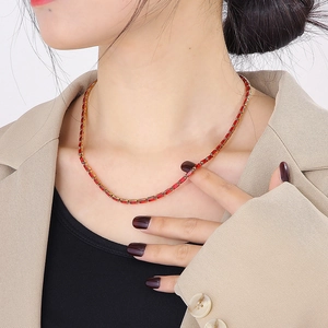 Vintage gold necklace with rectangular ruby zirconias worn by a model in a beige suit