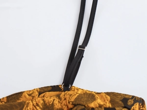 Dettaglio del cinturino nero regolabile con fibbia su tessuto jacquard floreale dorato