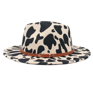 Wide brim wool felt fedora hat featuring black and white cow print and brown leather belt