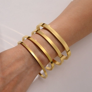 Set of five polished gold stainless steel C-shaped open bangles in varying widths