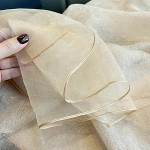Close-up of champagne silk scarf fabric showing elegant drape and subtle golden shimmer