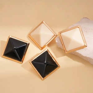 Close-up of geometric square resin earrings with gold trim in black and cream white