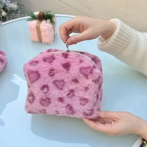 Pink heart leopard plush cosmetic bag held by hand, soft faux fur travel organizer
