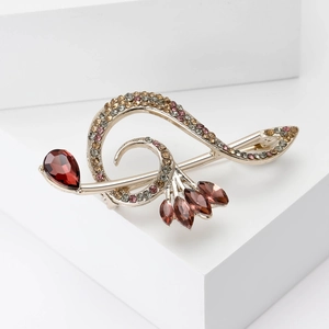 Detailed close-up of golden note brooch with multicolored rhinestones and crystals