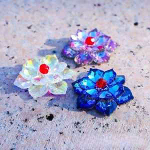 Close-up of three K9 crystal lotus flowers in purple, blue, and clear with red center