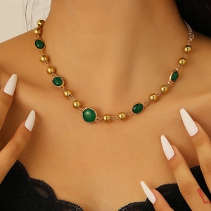 Nahaufnahme von Vintage-Goldperlen und grünen Steinen an einer zarten Choker-Halskette