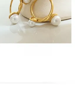 Macro detail of gold twist hoop earrings featuring elegant white pearls and vintage texture