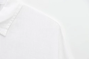 Close-up of white shirt collar and shoulder with natural linen fabric texture