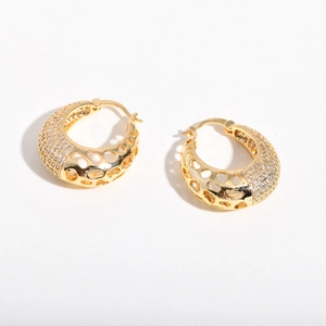 Detailed view of gold earrings with openwork geometric patterns and micro-pave zircons