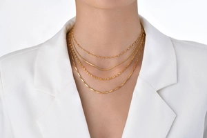 Close-up of four layered 18K gold-plated stainless steel chains on a model in a white suit