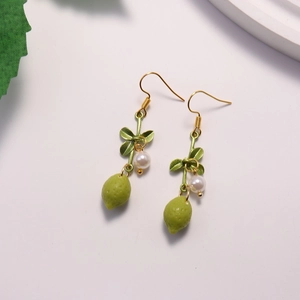 Detailed close-up of yellow lemon-shaped earrings with green leaves and white pearl accents