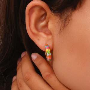 Close-up of a model wearing retro checkered hoop earrings with colorful oil drip enamel