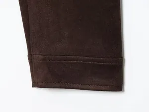 Gros plan sur la texture du daim marron foncé et les détails de double couture