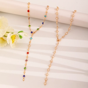 Detail of gold Y-shaped necklaces featuring colorful crystals and elegant white pearls