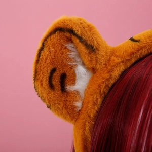 Close-up of orange plush tiger ear headband with black stripes and soft white inner detail