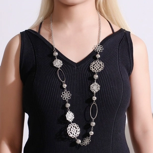Detail of bohemian silver body chain with hollow flower charms and metal beads on model