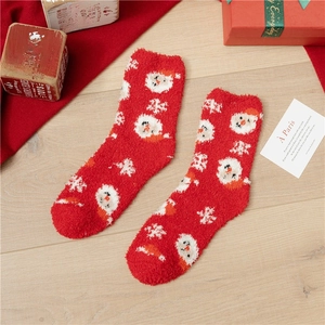 Close-up of red plush Christmas socks with Santa Claus pattern on a wooden floor