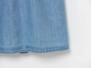 Detailed macro view of light blue denim fabric with precise double-row stitching detail