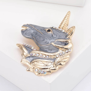 Detailed view of unicorn brooch with gold finish, grey enamel, and sparkling rhinestones