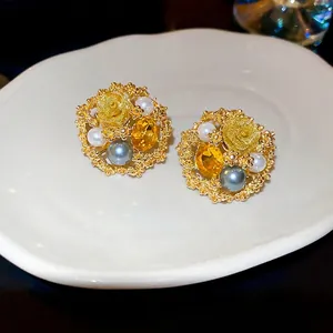 Vintage gold flower earrings with pearls and crystals on a white porcelain dish
