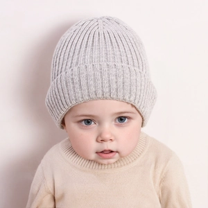 Close-up of light grey ribbed knit baby beanie with folded brim on a cute infant