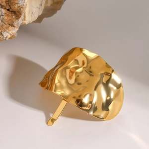 Detail of gold metal hair fork with textured hammered finish on a natural rock surface