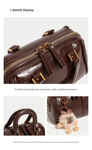 Close-up of brown Boston bag showing oiled leather texture and gold zipper details