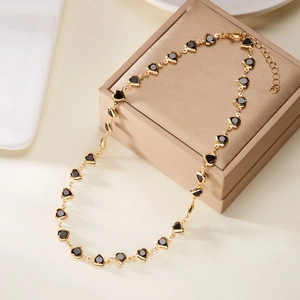 Detailed view of elegant golden necklace featuring multiple black heart-shaped gemstones