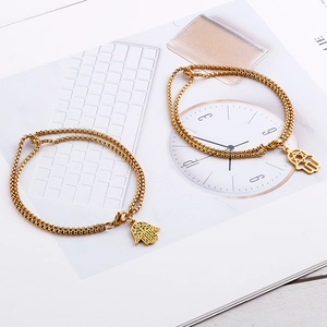 Dettaglio di bracciali doppi in oro con mano di Fatima e stella su una rivista