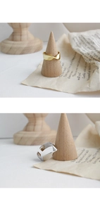 Detailed view of gold and silver Mobius twist rings on a wooden cone display