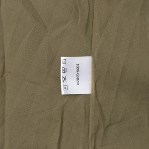 Détail de l'étiquette d'entretien 100 % coton sur un tissu de couleur vert olive