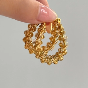 Detail of 18k gold plated spring coil earrings held to show unique wave texture