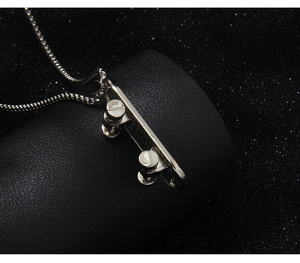 Vue macro d'un pendentif skateboard argenté avec gravure sur fond en cuir noir texturé