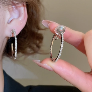 Detail view of sparkling silver hoop earrings with clear stones and silicone pads