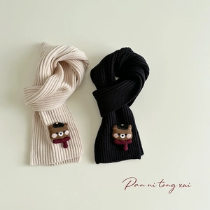 Detail of beige and black knitted scarves featuring cute teddy bear patches for kids