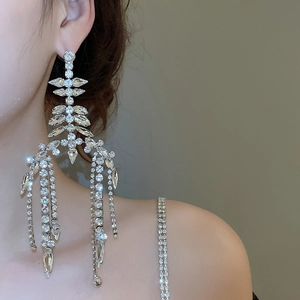 Macro detail of long silver fringe earrings with shimmering tassels on a female model